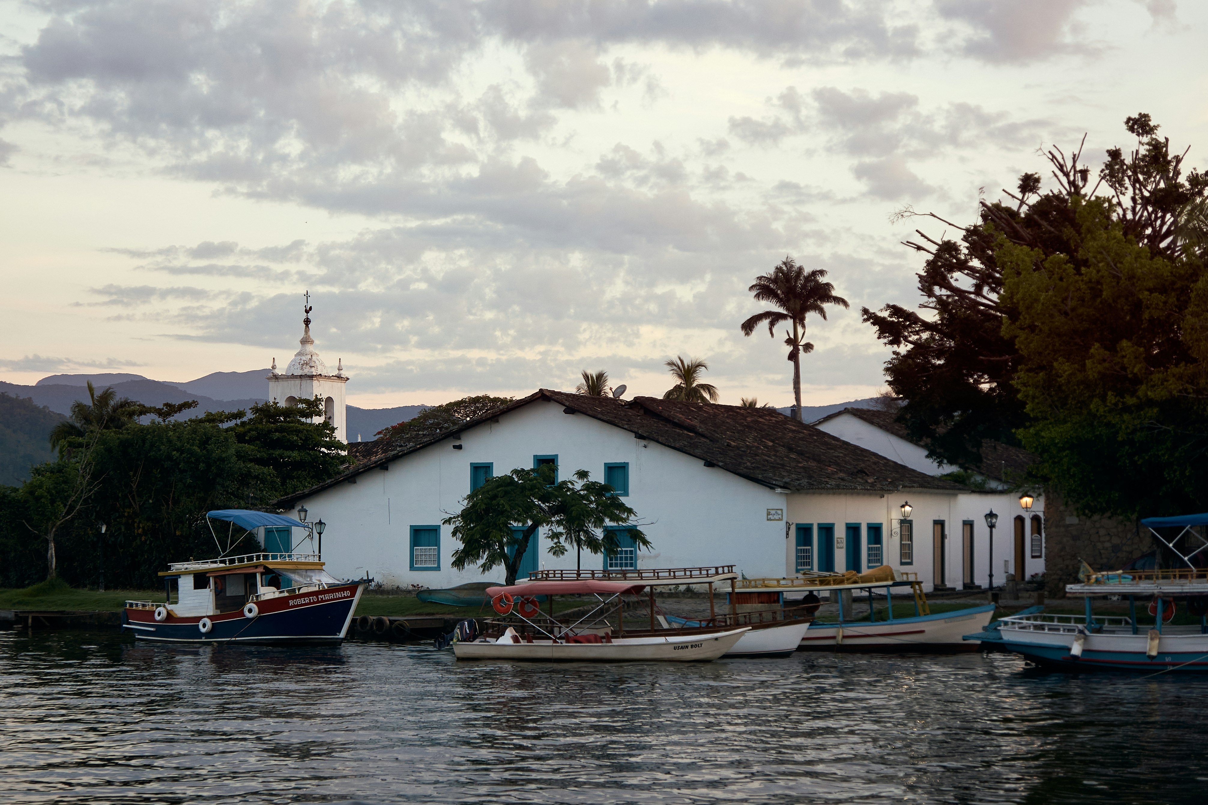 blue and white boat on water near houses under white clouds and blue sky during daytime